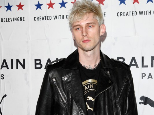 Machine Gun Kelly stares at the camera in a black leather jacket