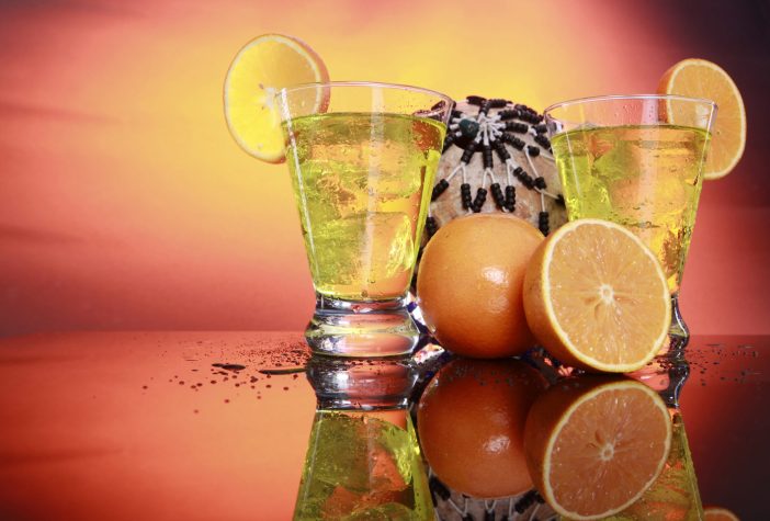 Glasses with a yellow beverage and orange slices.