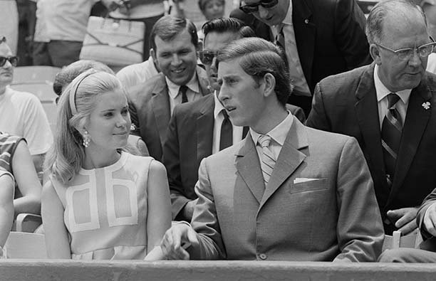 A black and white photo of a young Prince Charles sitting next to Tricia Nixon at a baseball game in