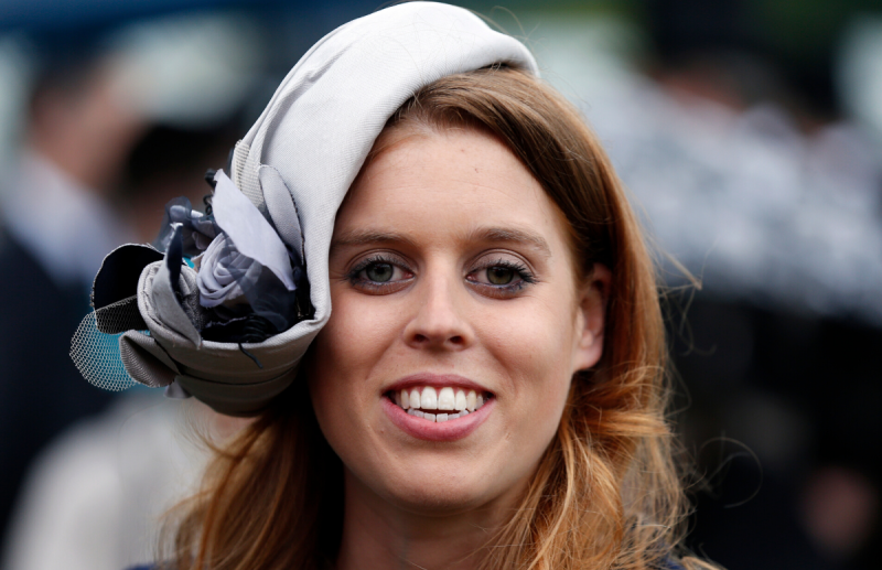 A close up of Princess Beatrice of York smiling and wearing a fashionable gray hat