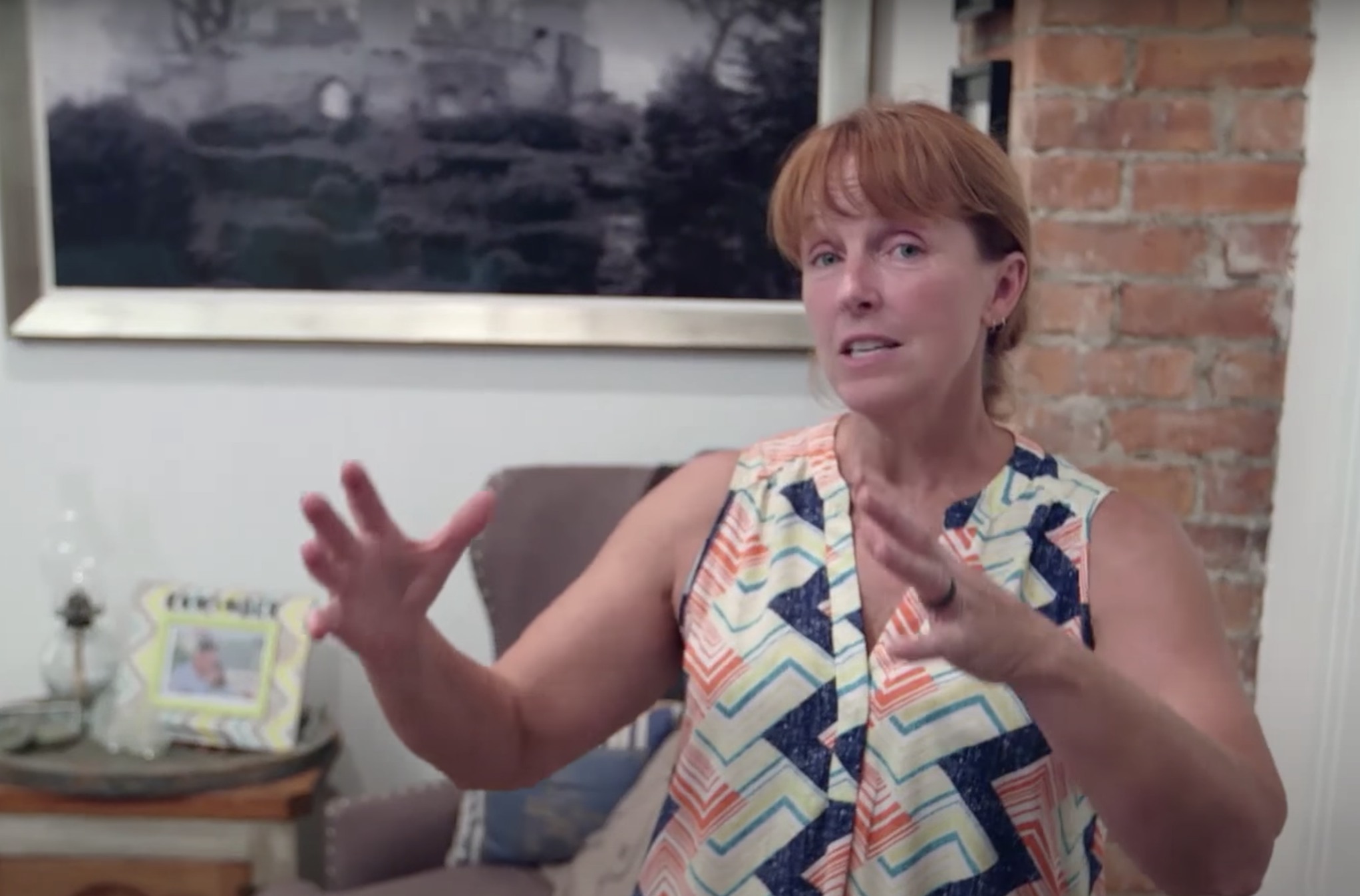 A screenshot featuring Karen Laine, wearing a multicolored top, giving a short tour of her home