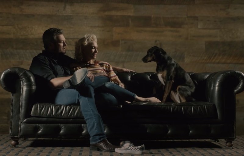 a still from Blake Shelton and Gwen Stefani's "Nobody But You" video of them sitting on a couch with