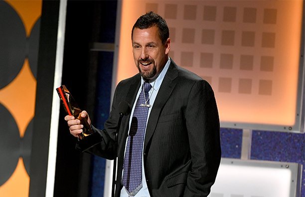 Adam Sandler on stage accepting an award