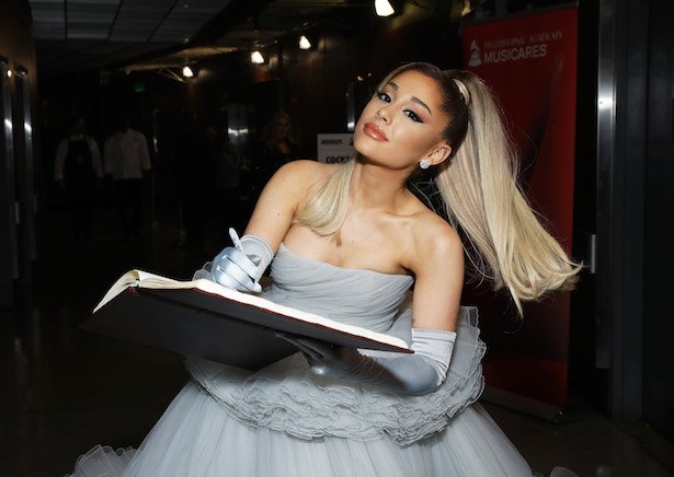Ariana Grande in a grey dress signing a book
