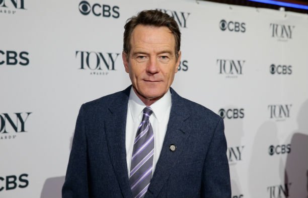 Bryan Cranston wearing a dark blue suit on the red carpet.