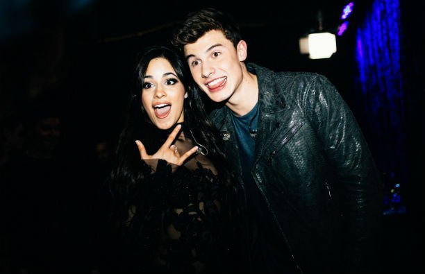 Camila Cabello in a black dress standing next to Shawn Mendes, who's wearing a black leather jacket