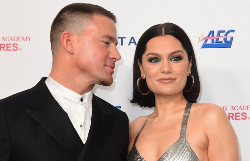 Channing Tatum wearing a black suit standing with Jessie J, who's wearing a silver dress, on the red