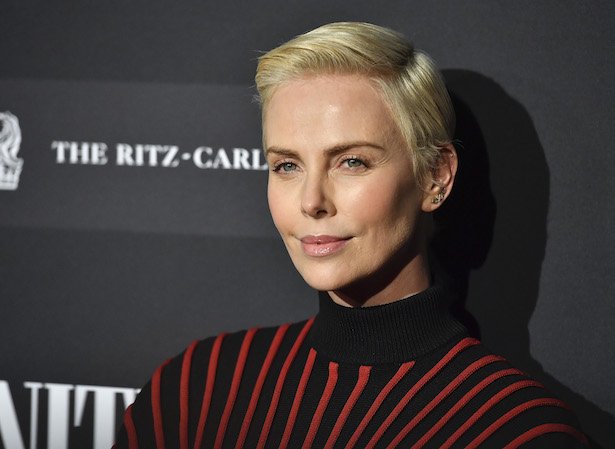 Charlize Theron in a black and red turtleneck against a black background