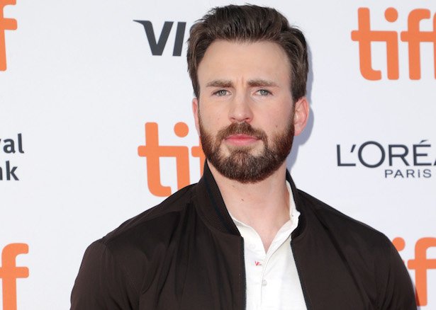 Chris Evans in a dark brown bomber jacket over a white polo on a white background