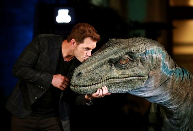 Chris Pratt in a black outfit kisses Blue the dinosaur