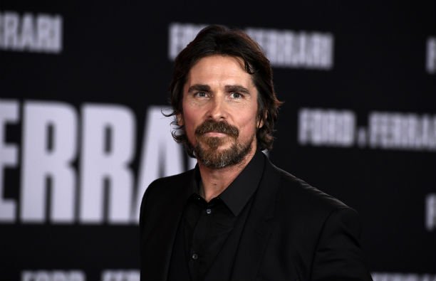 Christian Bale wearing an all black suit on the red carpet