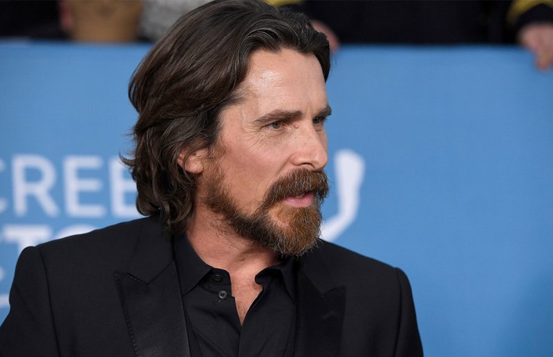 Christian Bale with a beard, in a black suit.