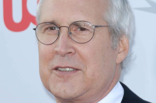 Close up of Chevy Chase wearing glasses at a red carpet event.