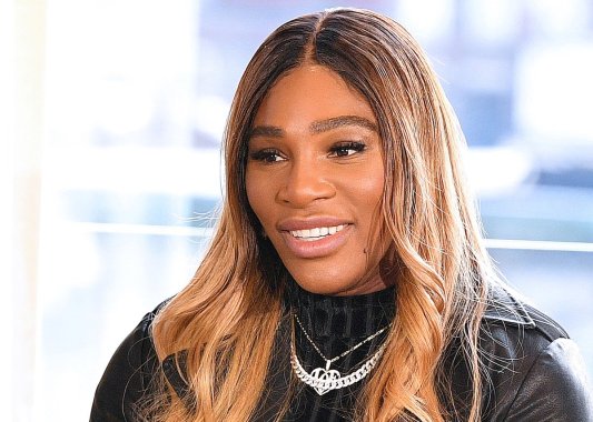 close up shot of Serena Williams smiling in a black top with silver jewelry