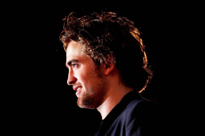Close up side profile of Robert Pattinson in a dark suit at a Twilight premiere