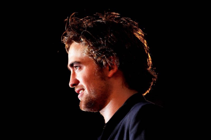 Close up side profile of Robert Pattinson in a dark suit at a Twilight premiere