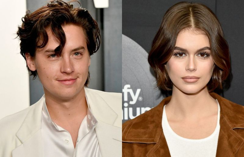 Cole Sprouse wearing a white suit on the red carpet. Kaia Gerber wearing a brown jacket on the red c