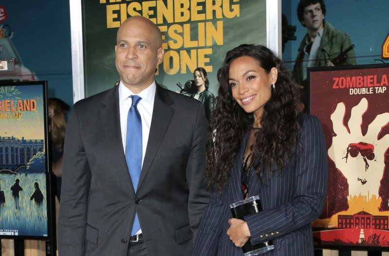Cory Booker, in a suit, poses with Rosario Dawson at the premiere of Zombieland Double Tap