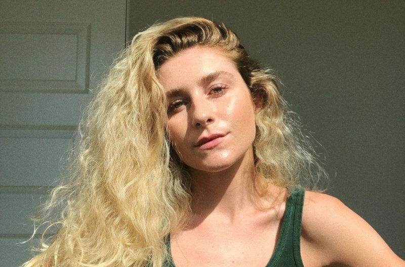 Courtney Taylor Olsen sporting long curly blonde hair and wearing green tanktop