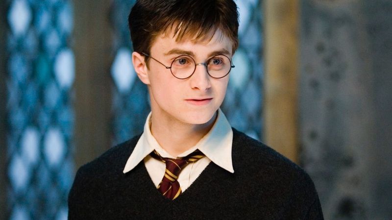 Daniel Radcliffe as Harry Potter looks to his left in a Hogwarts uniform