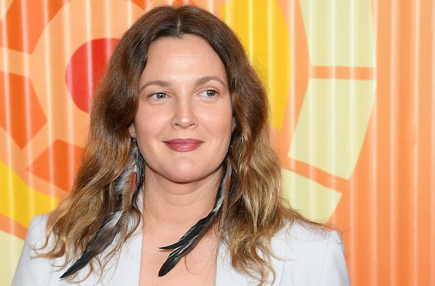 Drew Barrymore in a white suit jacket with feathered earrings