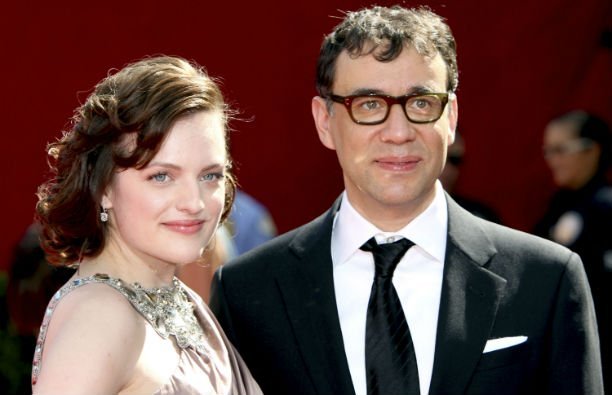 Elisabeth Moss in a pale blush colored dress standing with Fred Armisen, who's wearing a black suit,