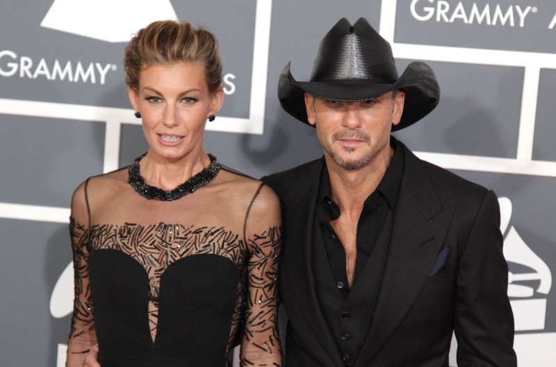Faith Hill and Tim McGraw, both dressed in all black, walk the red carpet at the Grammy Awards