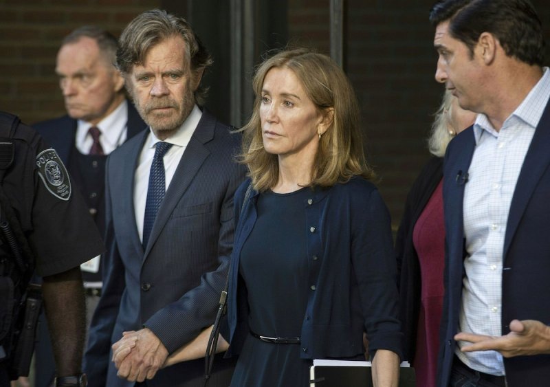 Felicity Huffman in a dark dress and cardigan walks hand in hand with William H. Macy in a suit at t