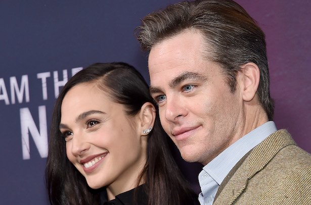 Gal Gadot in black smiling next to Chris Pine in a tan and blue suit