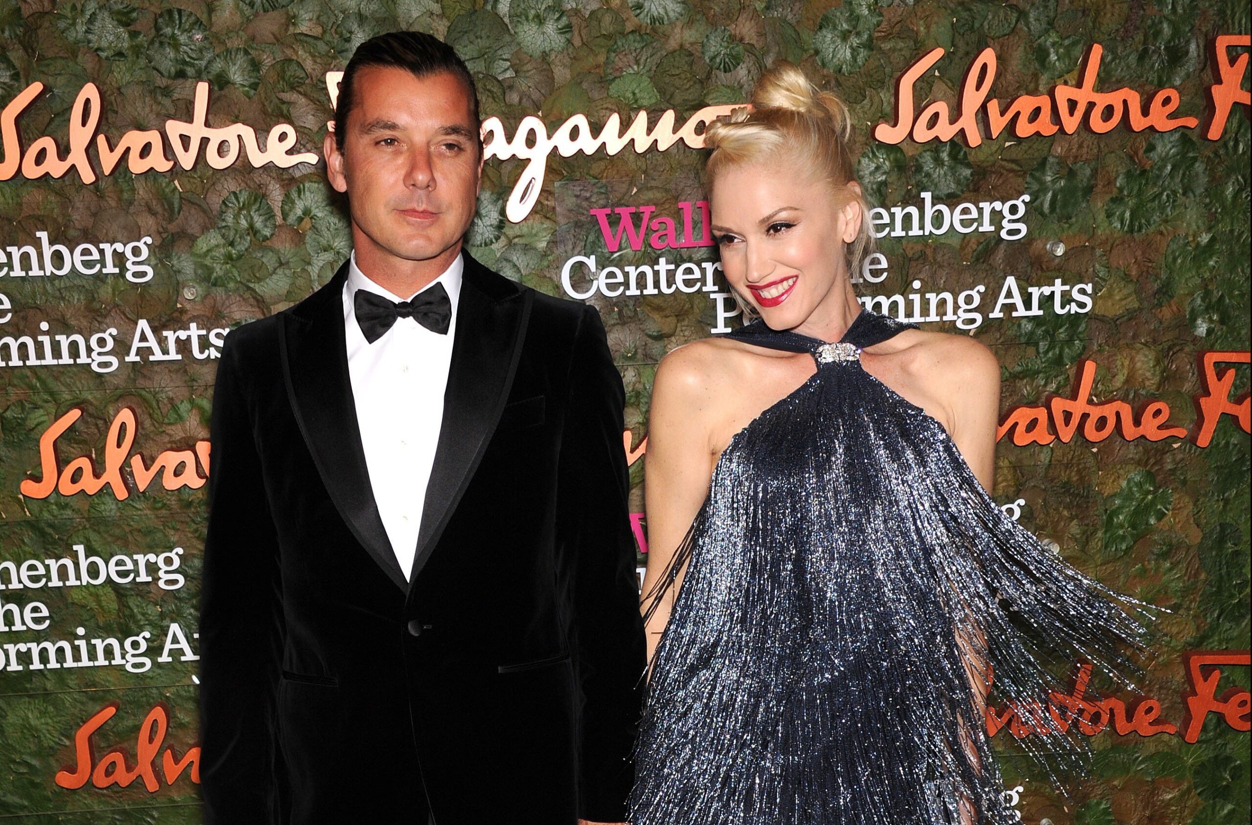 Gavin Rossdale, in a black tux, stands with Gwen Stefani, in a feathery dress