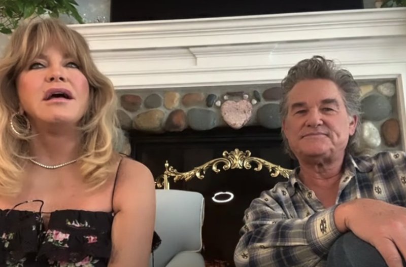 Goldie Hawn wearing a floral print dress sits with Kurt Russell, in a flannel, on The Ellen Show