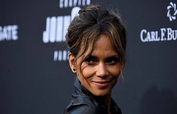 Halle Berry looking over her shoulder and smiling on at a red carpet event.