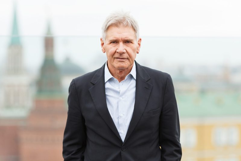 Harrison Ford wearing a black suit with no tie during a photo call session