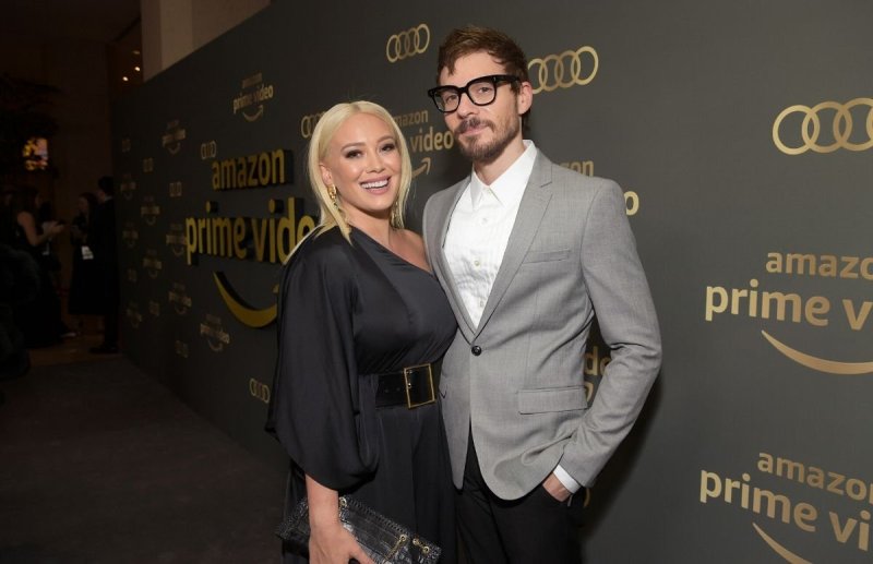 Hilary Duff in a black dress standing with Matthew Koma, who's wearing a gray blazer and black pants