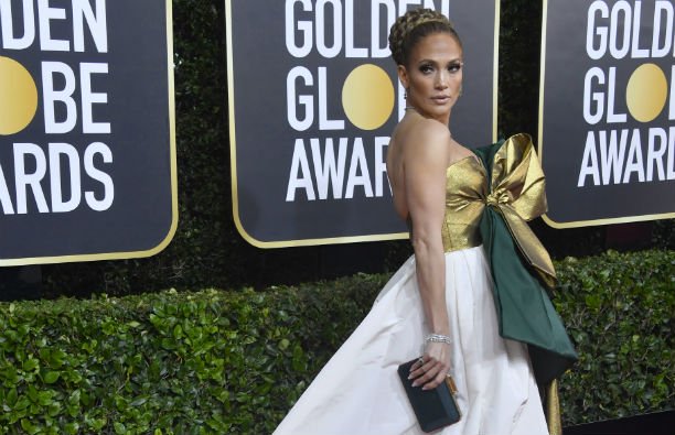 Jennifer Lopez in a white, gold, and green dress on the Golden Globe red carpet