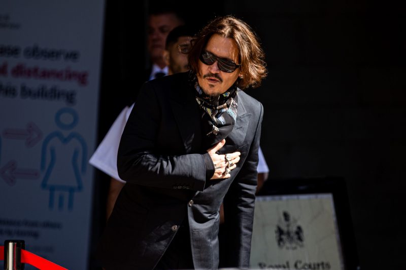 Johnny Depp in a black jacket and sunglasses walking out of court in July 2020.