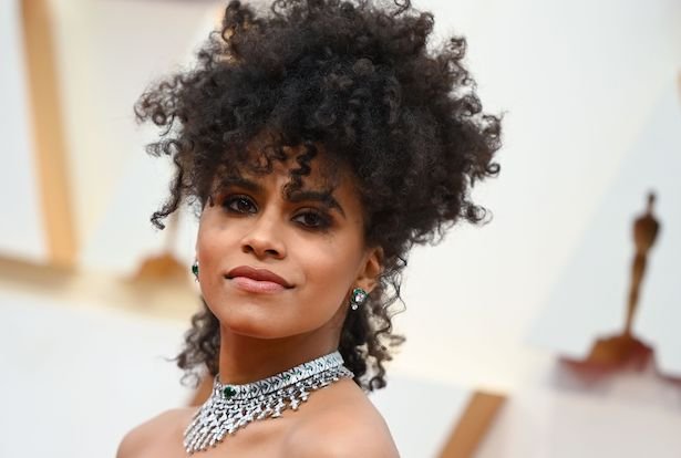 Joker actress Zazie Beetz with an elaborate silver necklace and natural hair on a white background