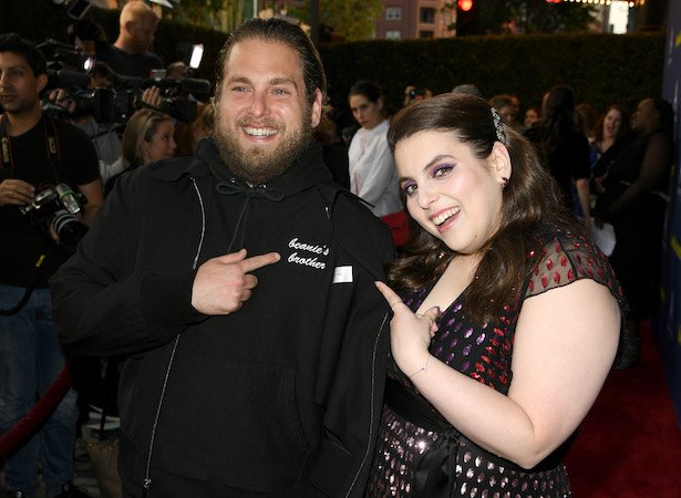 Jonah Hill in a black hoodie with Beanie's Brother printed on it and Beanie Feldstein in a dark dres