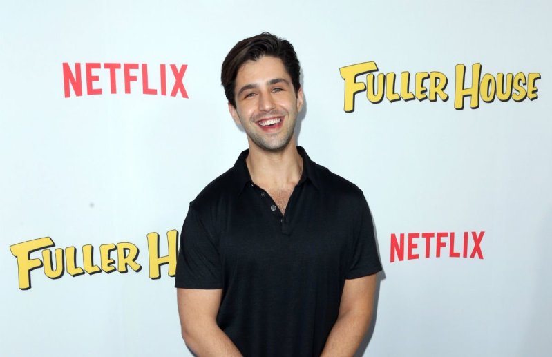 Josh Peck wearing a black polo shirt on the red carpet.