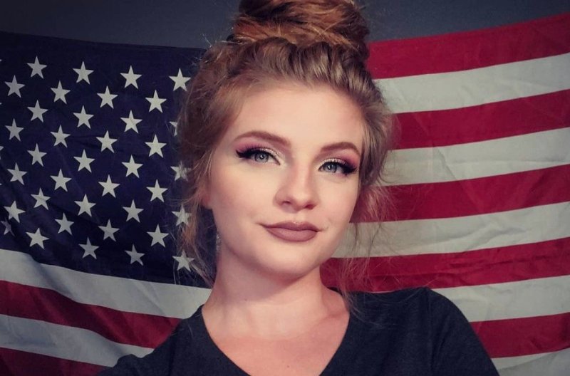Kaitlin Bennett taking a selfie in front of an American flag