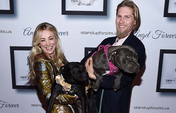 Kaley Cuoco on the left holding a dog with her husband, Karl Cook at a charity event