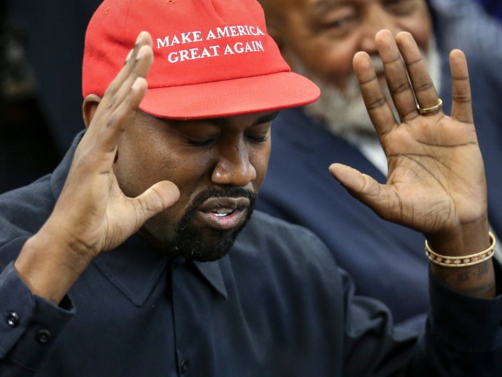 Kanye West, wearing a black button down shirt and a red MAGA hat, visiting President Donald J. Trump