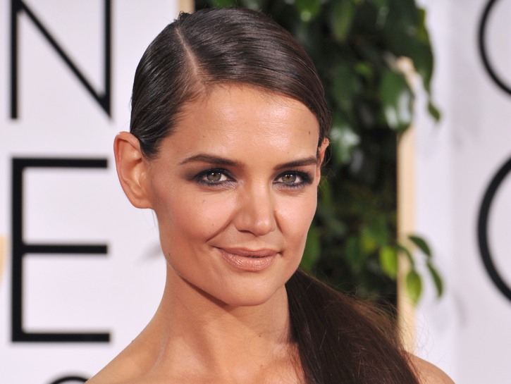 Katie Holmes with her hair in a ponytail and wearing a purple strapless dress to the Golden Globes