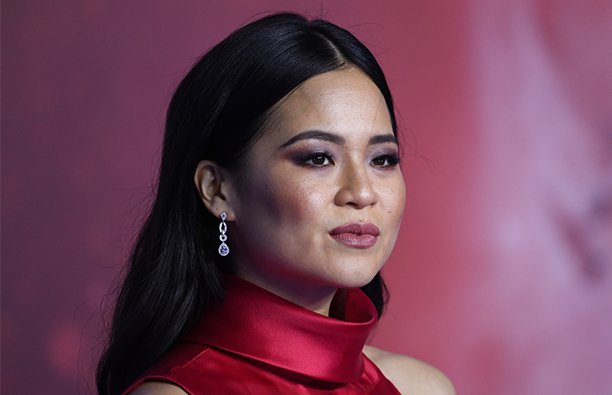 Kelly Marie Tran in a red dress in front of a red background