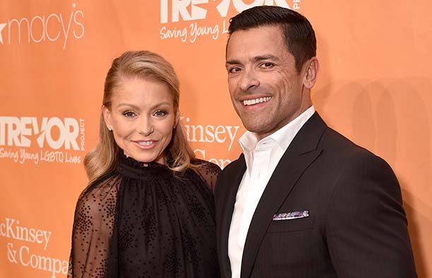 Kelly Ripa in a black dress standing next to Mark Consuelos in a dark suit.