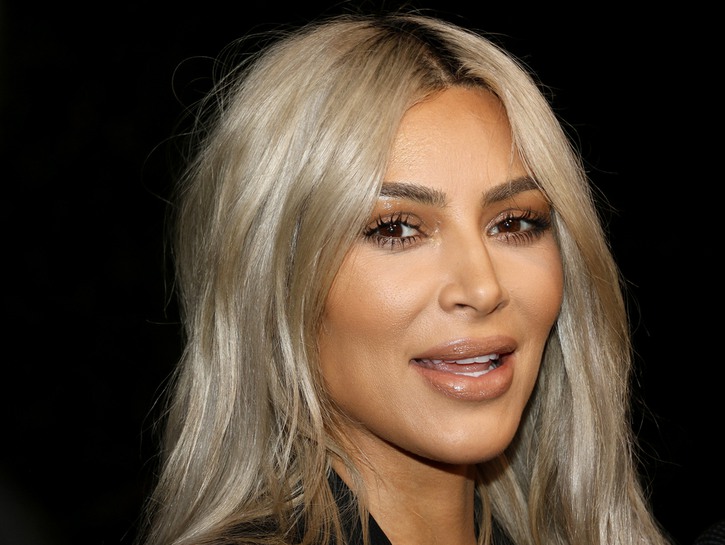 Kim Kardashian has dirty, white blonde hair in this photo, which is against a black backdrop.