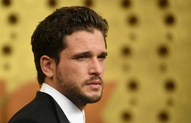 Kit Harington wearing a black suit on the red carpet.
