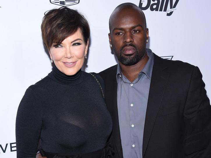 Kris Jenner, wearing all black, poses with Corey Gamble, who's wearing a black blazer