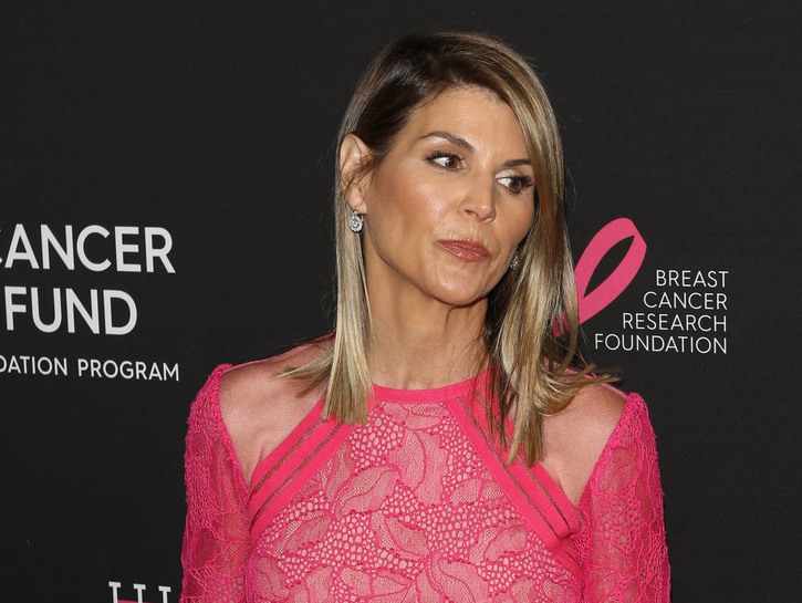 Lori Loughlin in a pink dress, looking concerned at an event right before the college admission scandal broke last year. She is sentenced to two months behind bars for her crimes.