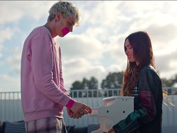 Machine Gun Kelly's Bloody Valentine video still of Kelly in a pink sweater and Megan Fox in leather